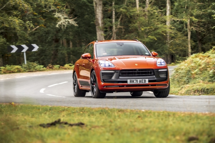 Orange Porsche Macan GTS driving on a winding road