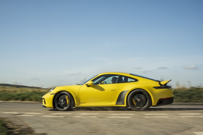 Yellow Porsche 911 Carrera GTS driving on road