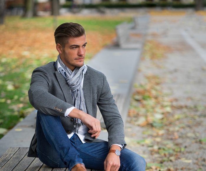 Man in jacket and scarf sitting on bench