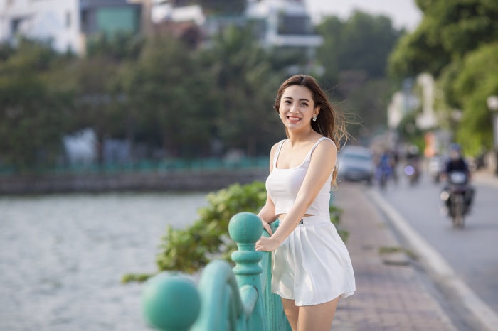 Asian woman in white outfit by a railing