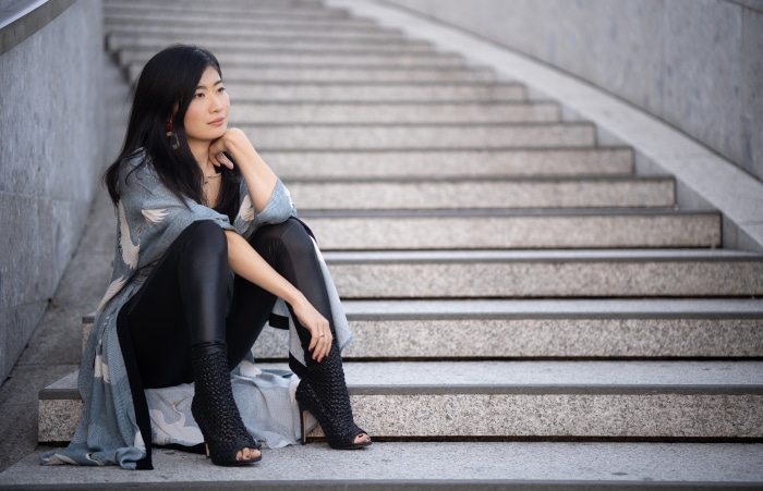 Asian woman with black hair sitting on stairs