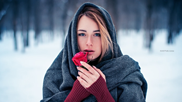 Woman in a grey scarf holding a red rose
