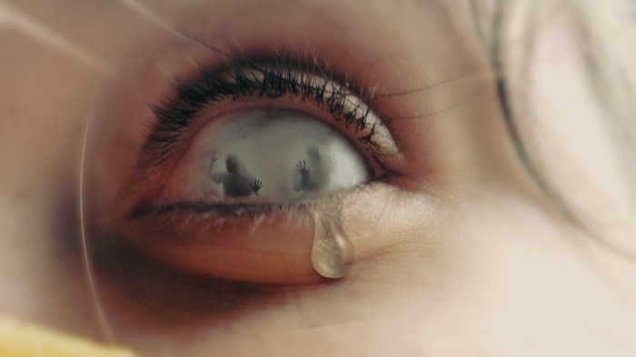 Close-up of a crying eye with figures trapped inside