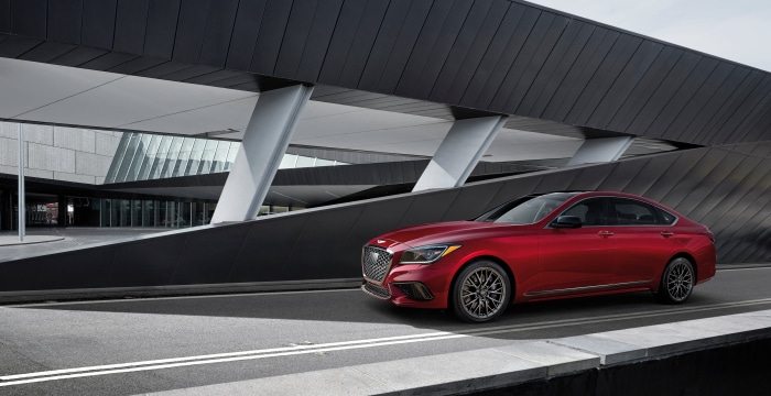 Red Genesis G80 Sedan parked near modern architecture