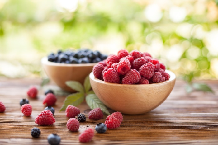 Raspberries and blueberries in wooden bowls