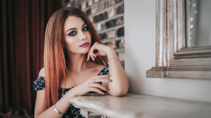 Woman with long auburn hair and dark makeup