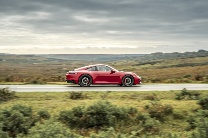 Red Porsche 911 Carrera GTS driving on a road