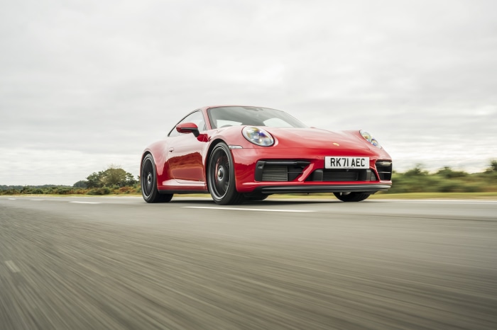 Red Porsche 911 Carrera GTS driving on a road