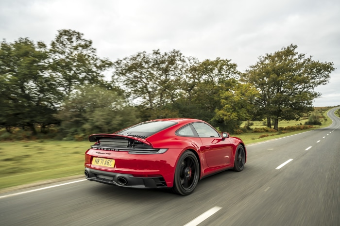 Red Porsche 911 Carrera GTS driving on a road