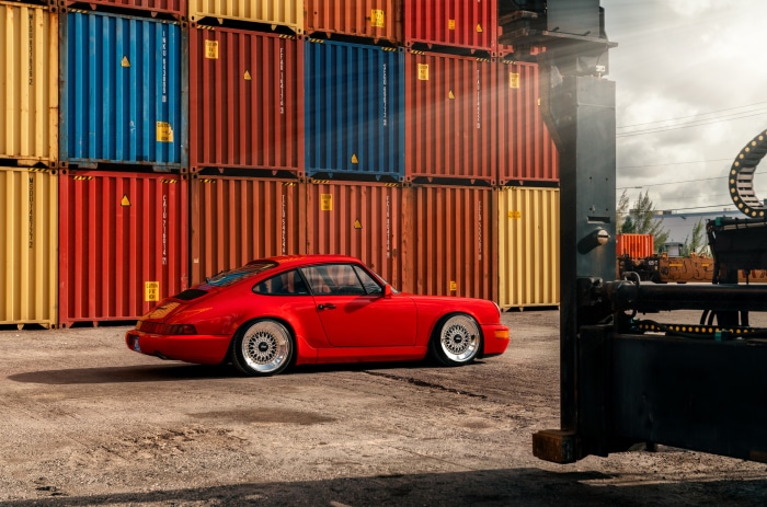 Red Porsche 964 Turbo parked near shipping containers