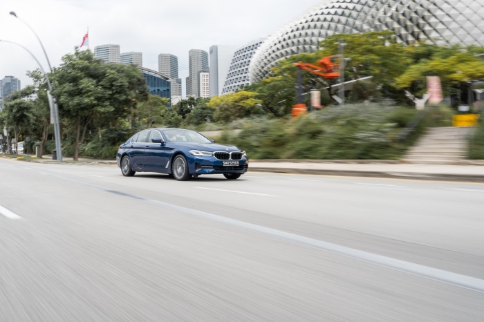 Blue BMW 5 Series 530e Luxury Line driving on road