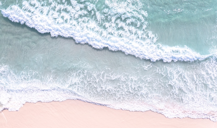 Aerial view of ocean waves crashing on a sandy beach