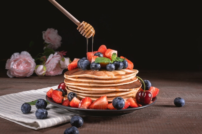 Stack of pancakes with berries and honey