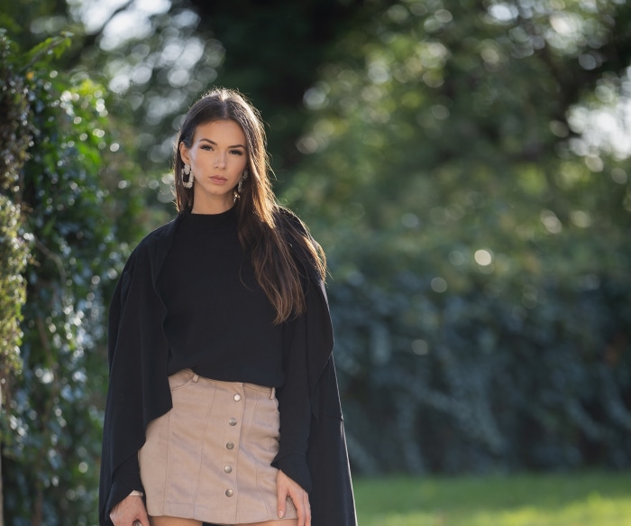 Brunette model in black top and beige skirt