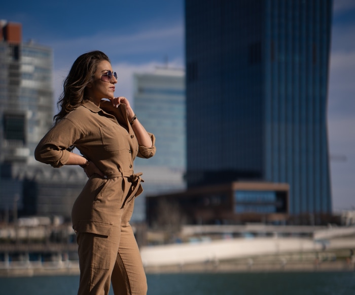 Woman in a jumpsuit with sunglasses in front of skyscrapers