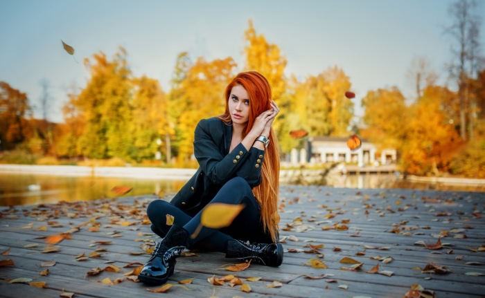Redhead woman sitting on a wooden pier in autumn