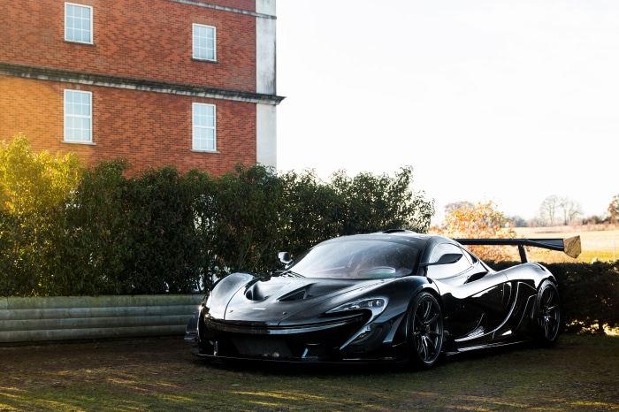 Black McLaren P1 supercar parked near a brick building