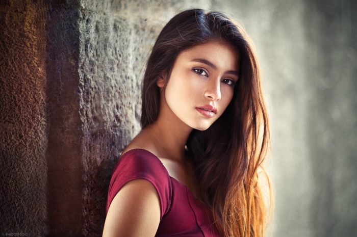 Brunette woman leaning against a stone wall