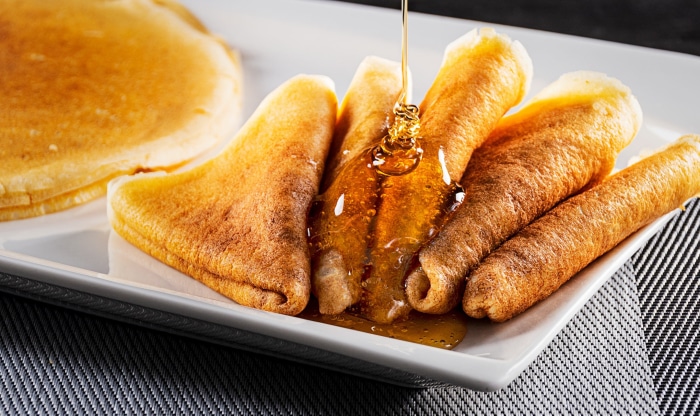 Rolled crepes with honey on a white plate