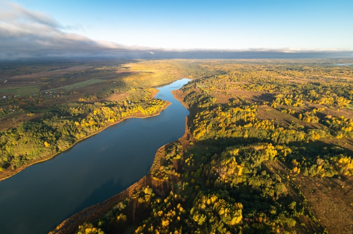Aerial view of a winding river through autumn forest