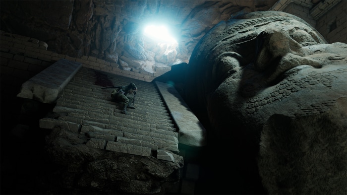 Man climbing stairs near giant statue in cave