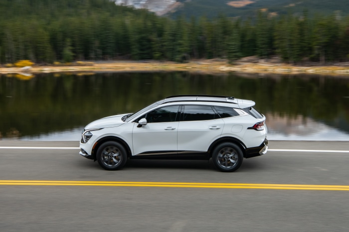 White Kia Sportage SX driving on road near lake