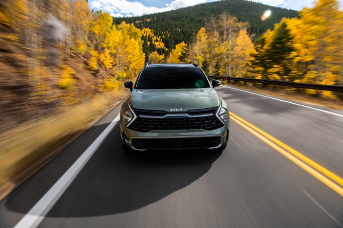 Kia Sportage X-Pro driving on a mountain road during autumn