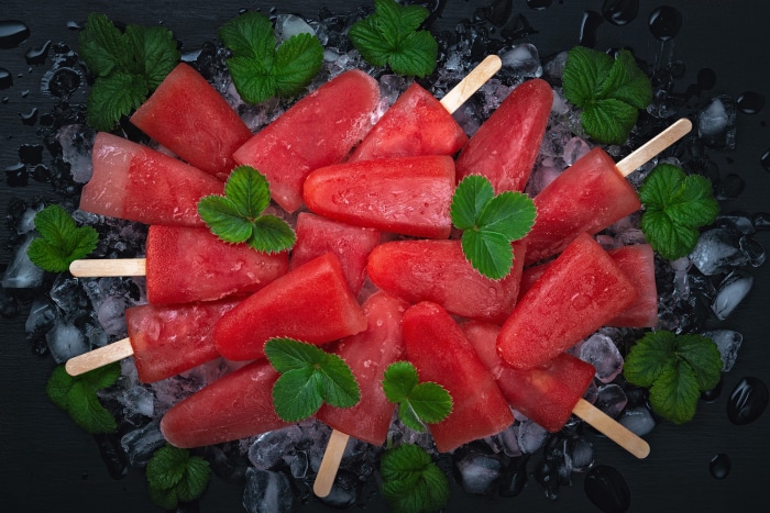 Watermelon popsicles on ice with mint leaves