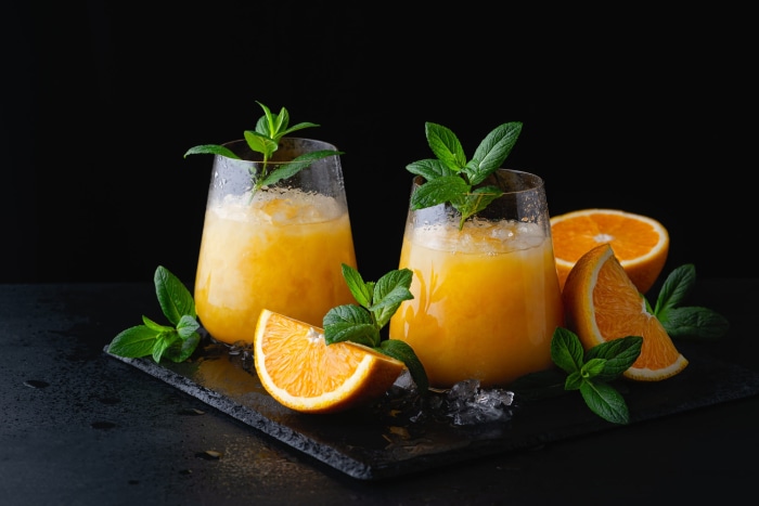 Two orange smoothies with mint and orange slices