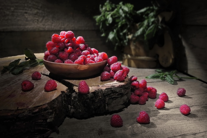 Raspberries in a bowl on a wooden surface
