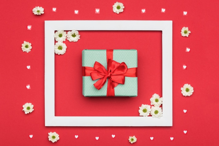 Gift with red ribbon and flowers on red background