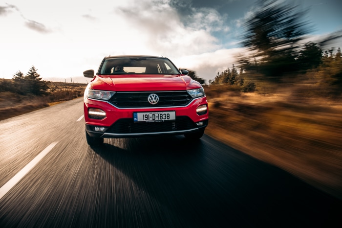 Red Volkswagen T-Roc driving on a road