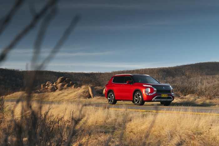 Red Mitsubishi Outlander driving on a road