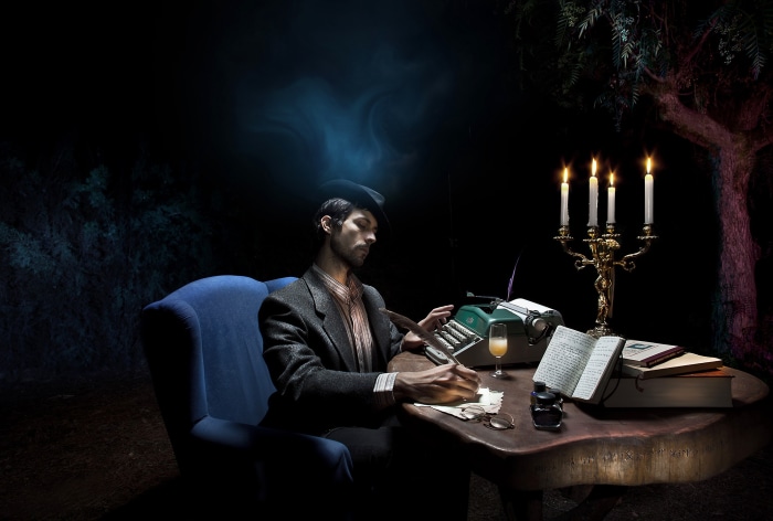 Man writing at a desk with a typewriter