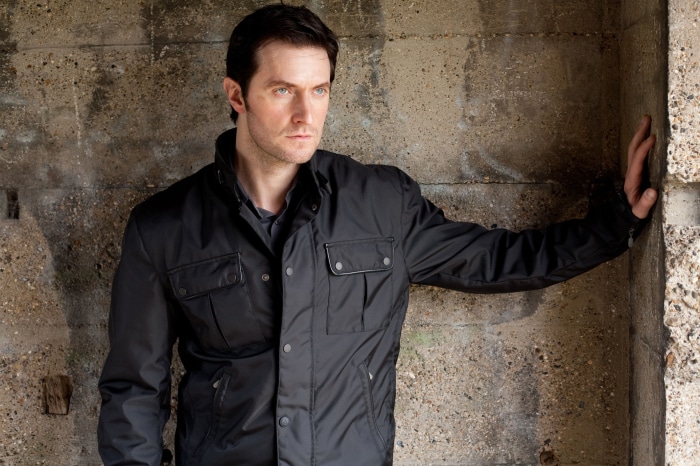 Richard Armitage leaning against concrete wall