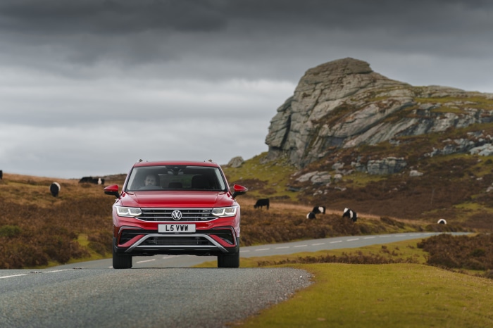 Red Volkswagen Tiguan Allspace on a road with cows