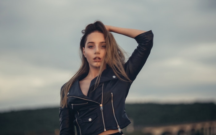 Woman in leather jacket with hand in hair