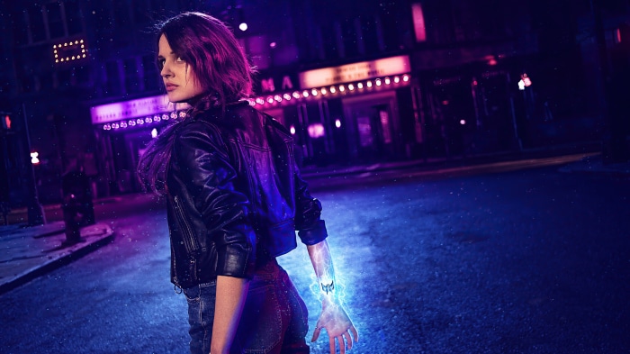 Woman with glowing arm in leather jacket at night