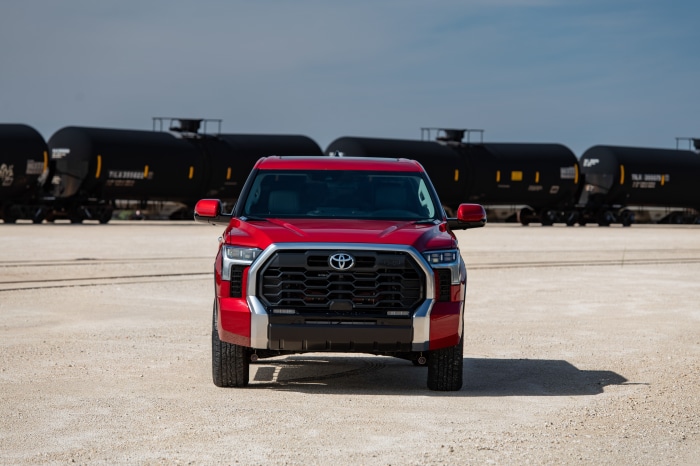 Red Toyota Tundra Limited CrewMax in front of train cars