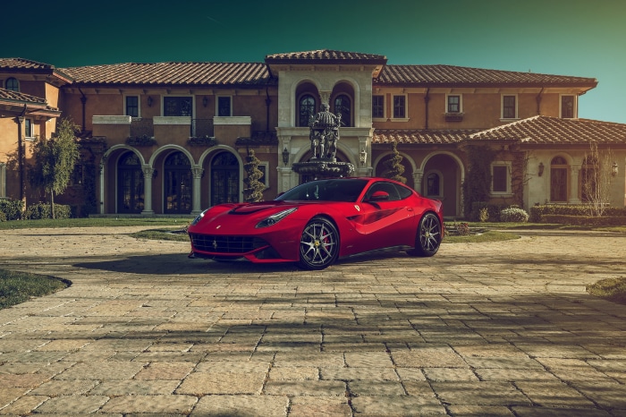 Red Ferrari F12berlinetta parked in front of a mansion