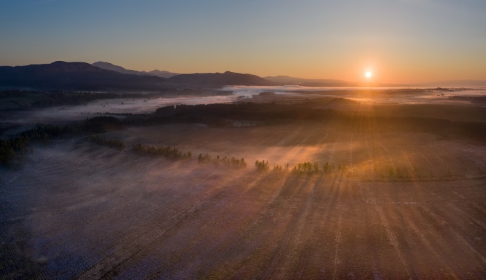 Sunrise over misty mountains and fields