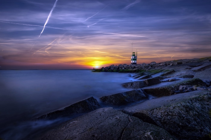 Lighthouse on rocky coast at sunset