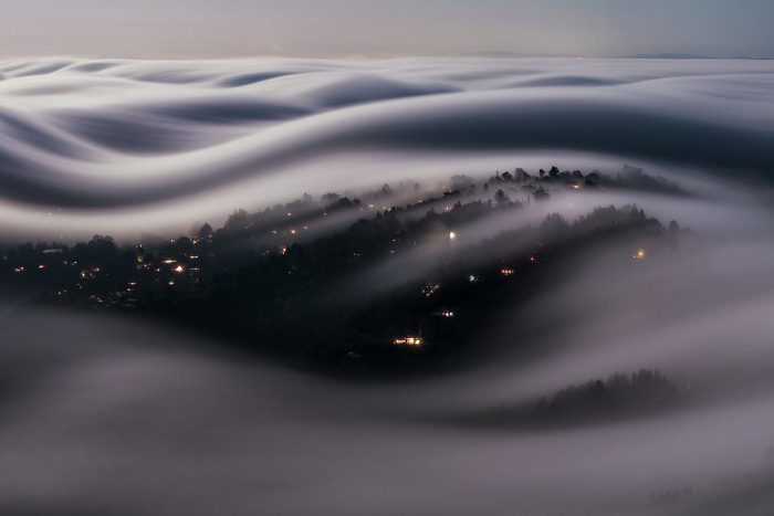 Foggy hills with glowing lights at dusk