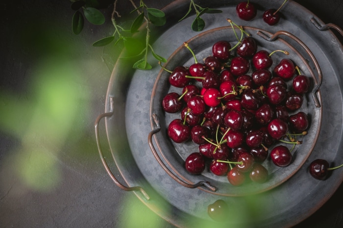 Cherries on a dark tray with leaves