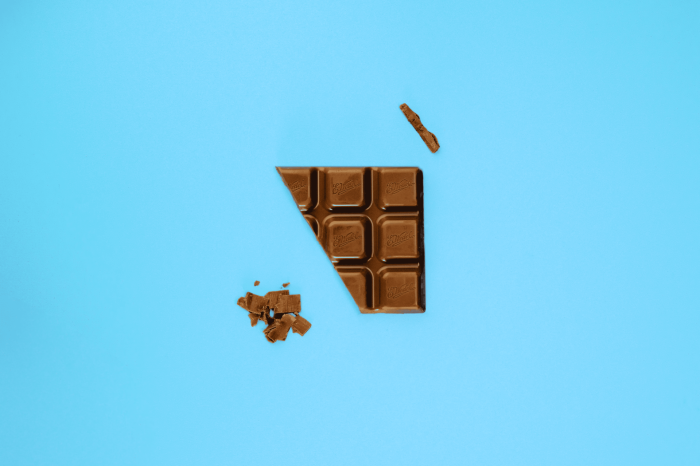 Chocolate bar with broken pieces on blue background