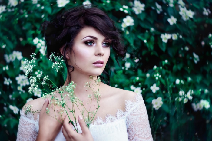 Woman with dark hair and white dress holding flowers