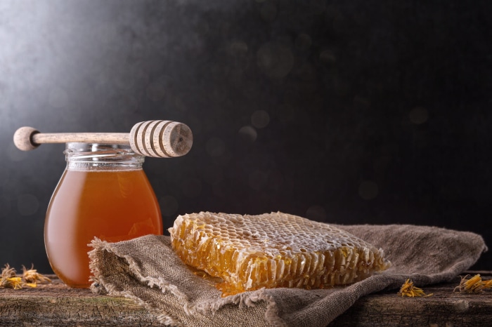 Honey in a jar with honeycomb and dipper