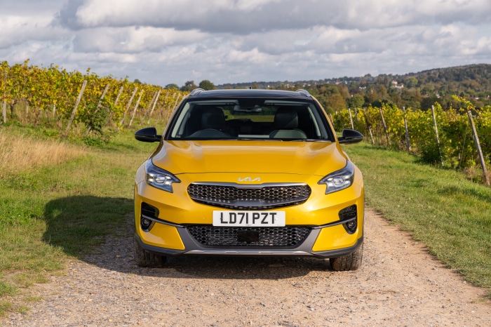 Yellow Kia XCeed SUV on a dirt road with vineyards