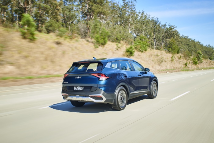 Blue Kia Sportage driving on a highway