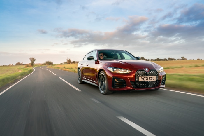 Red BMW M440i xDrive Gran Coupé driving on a country road